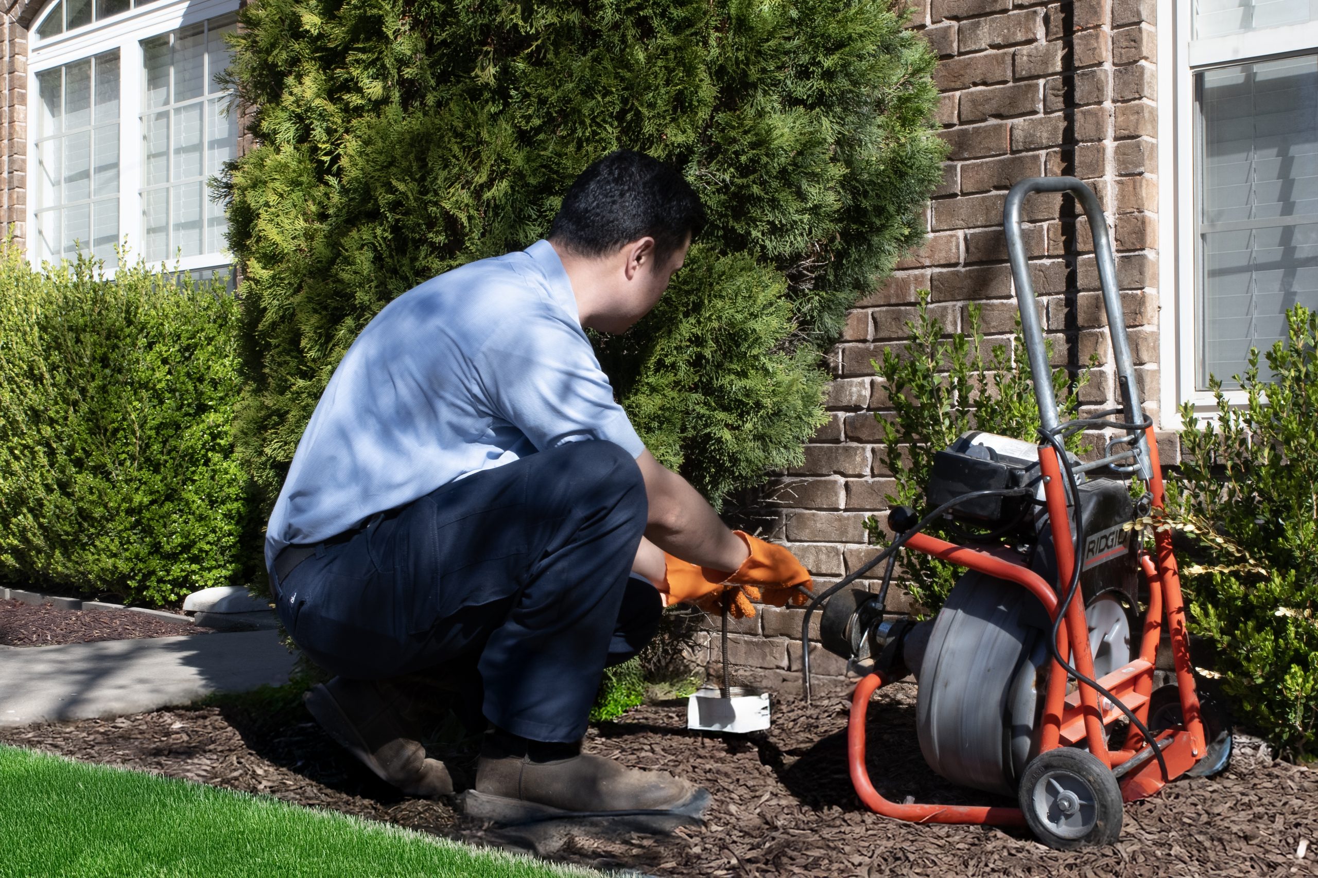 Plumber clearing a clogged drain backup
