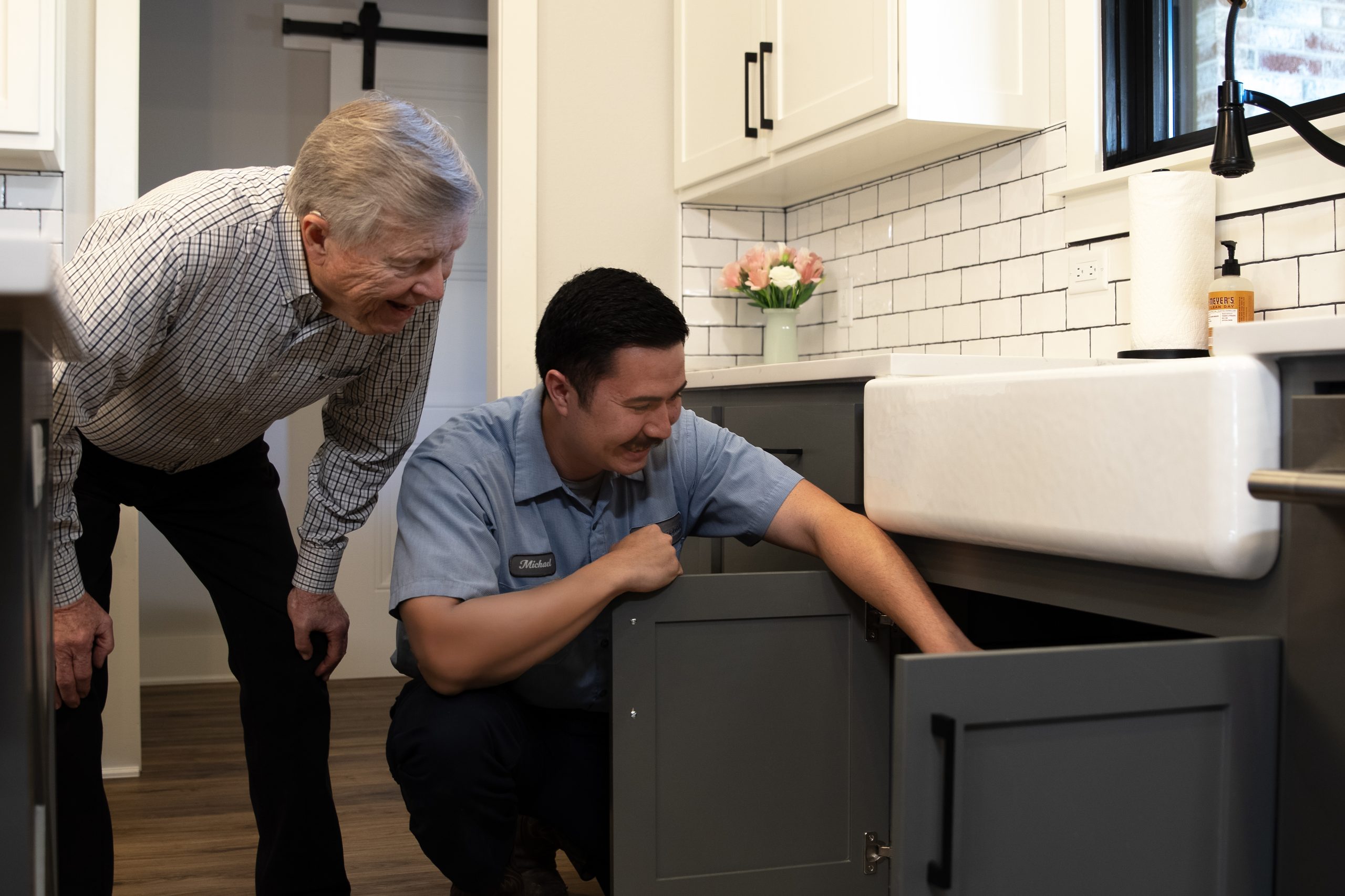 Licensed plumber diagnosing the issue under sink